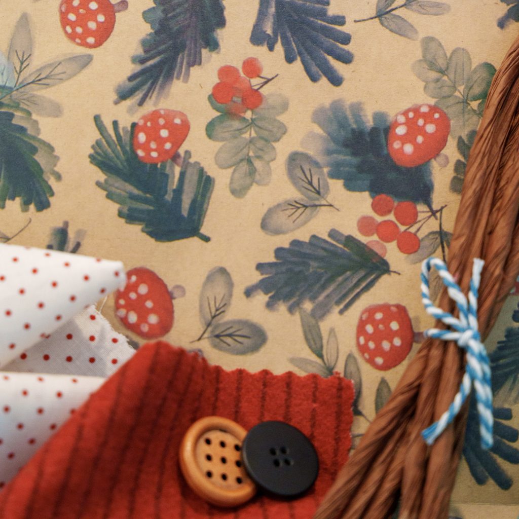 DIY fabric-and-paper craft kit materials with Mushroom & Pine paper featuring mushrooms, pine and berries, fabrics, raffia, buttons and string